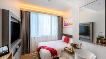 Una habitación de hotel con cama, televisión, mesita de noche y un espejo grande.