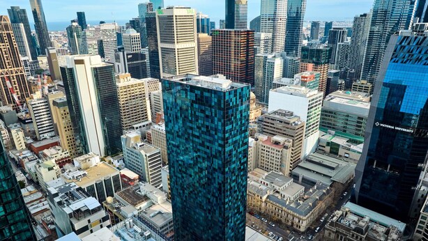 Un edificio de gran altura con una fachada azul distintiva, rodeado de otros edificios en un paisaje urbano.