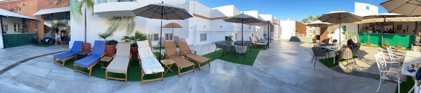 An outdoor patio area with lounge chairs, umbrellas, and a small table with chairs.