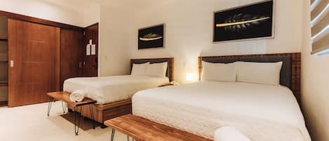 A hotel room with two beds, wooden headboards, a ceiling fan, and artwork on the walls.