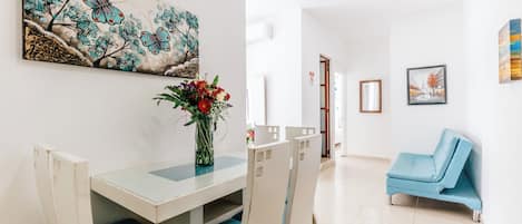 Un comedor con una mesa, sillas y un jarrón de flores.