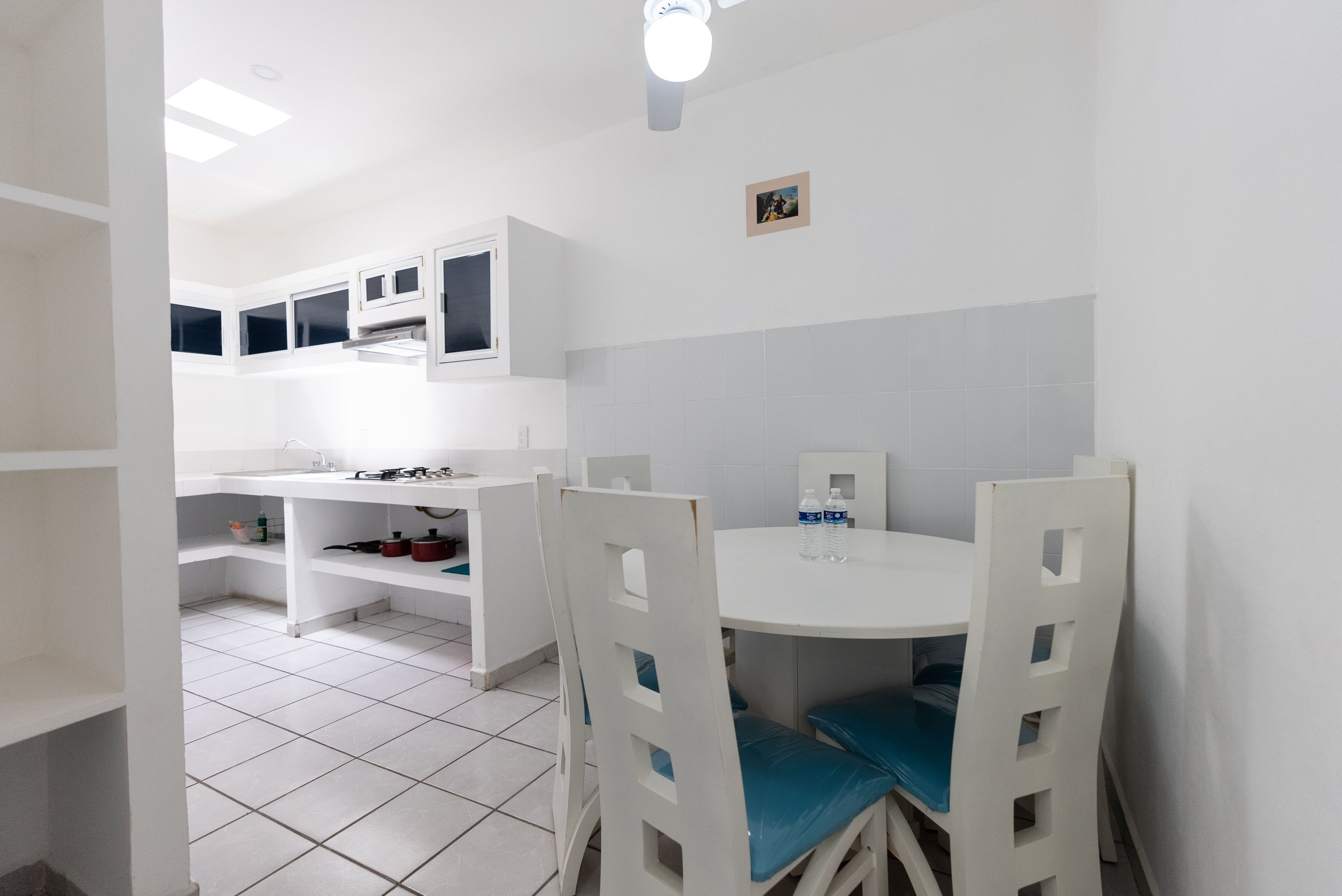 A modern kitchen with white cabinets, a round dining table, and blue chairs.