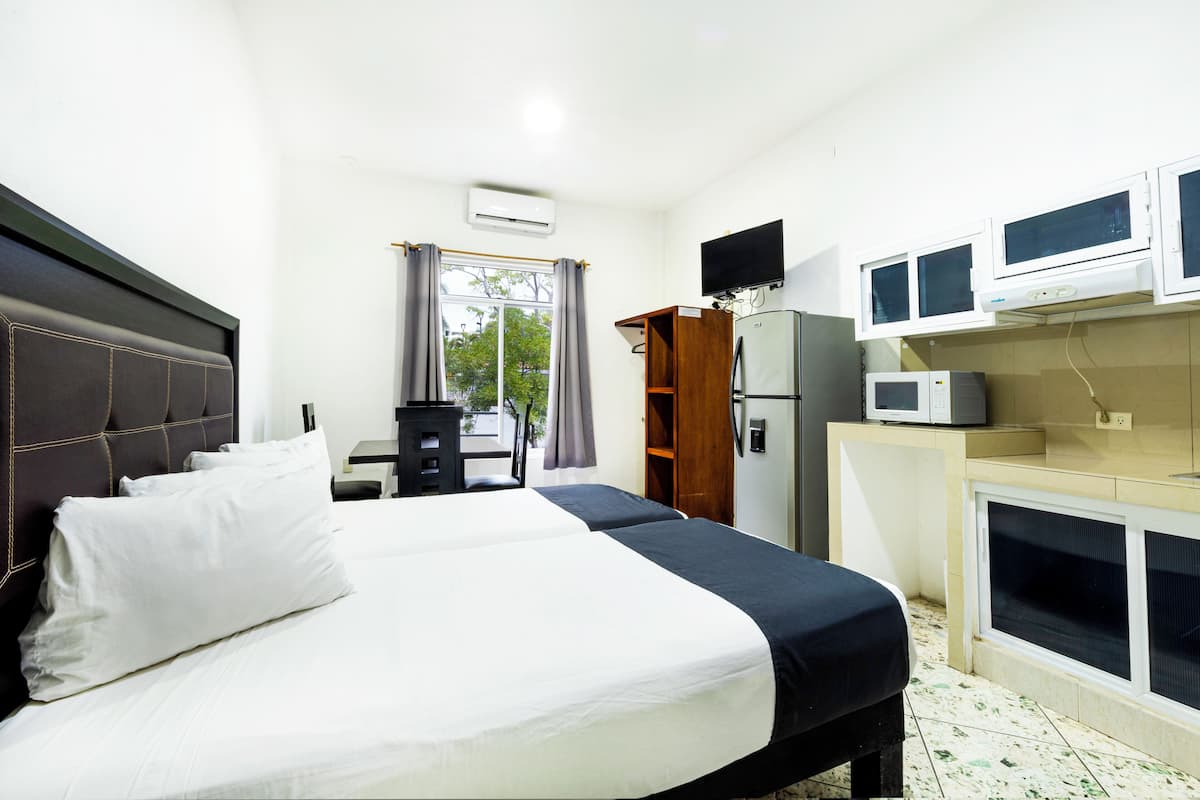 Een hotelkamer met een groot bed, een bureau, een kledingkast en een kitchenette.