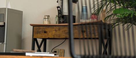 Una kitchenette con cafetera, una mesa de madera y una silla.