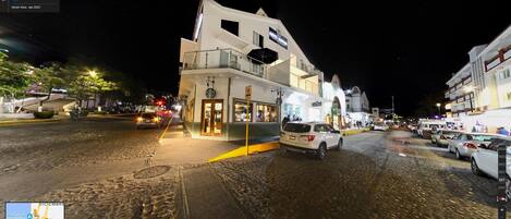 A street view of a hotel with a modern design, a visible restaurant, and a cobblestone street.