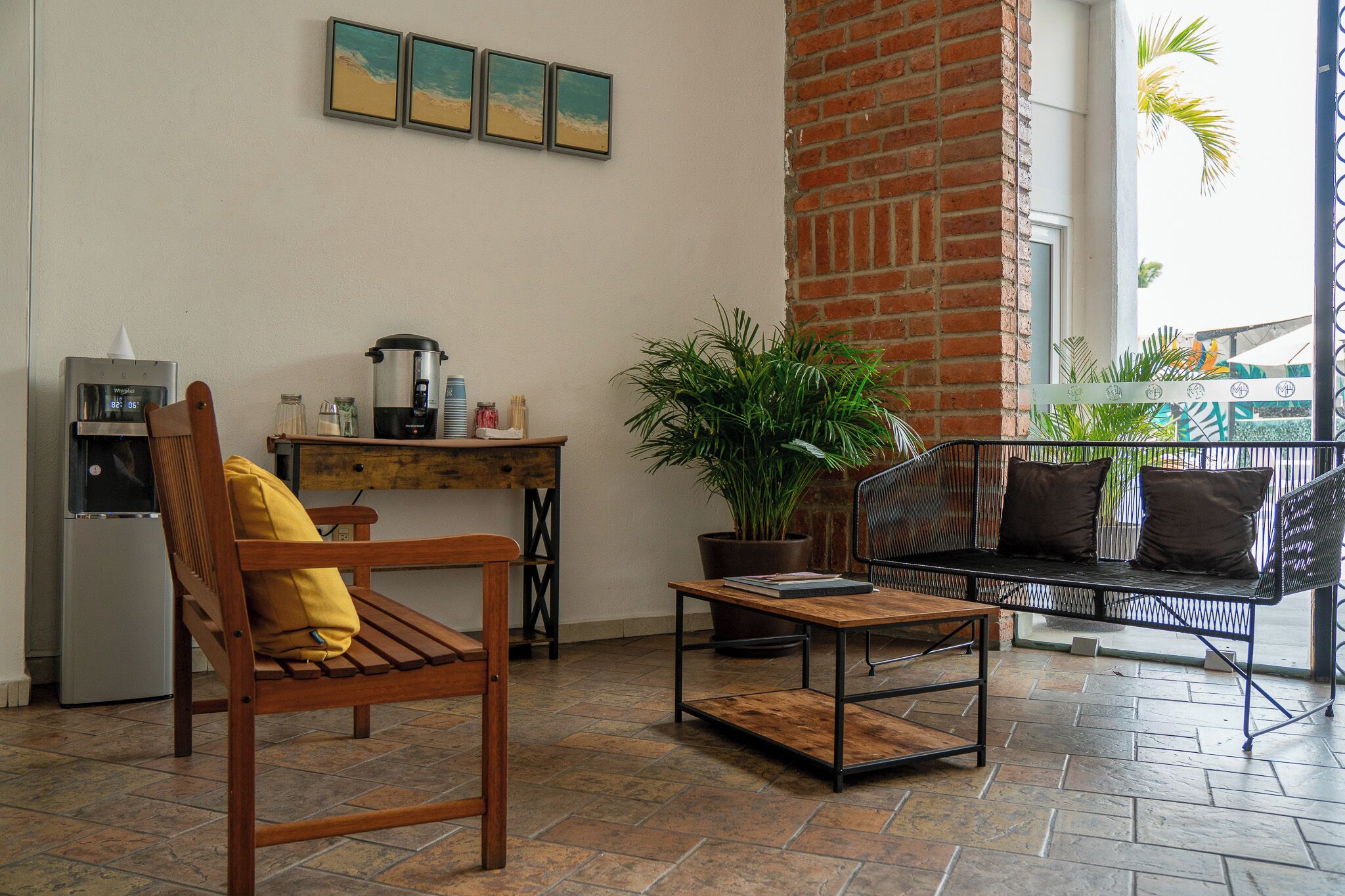 A cozy living area with a wooden chair, a metal sofa, a coffee table, and a potted plant.