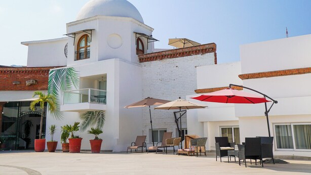 Un bâtiment à la façade blanche, surmonté d’un dôme et doté d’un balcon avec des chaises et des parasols.