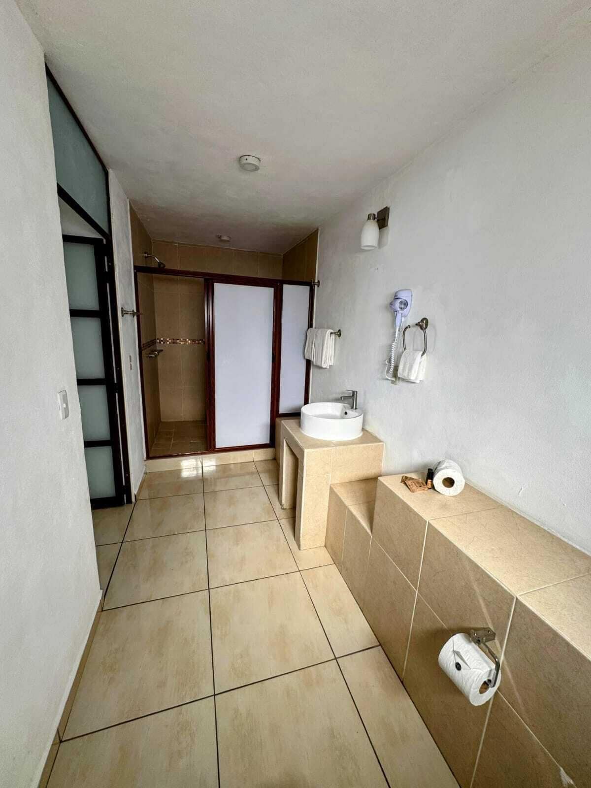 Un baño con lavamanos, toallero y dispensador de papel higiénico.