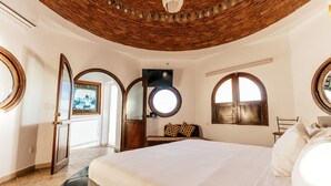 Une chambre avec un grand lit, un plafond en bois et une fenêtre ronde.