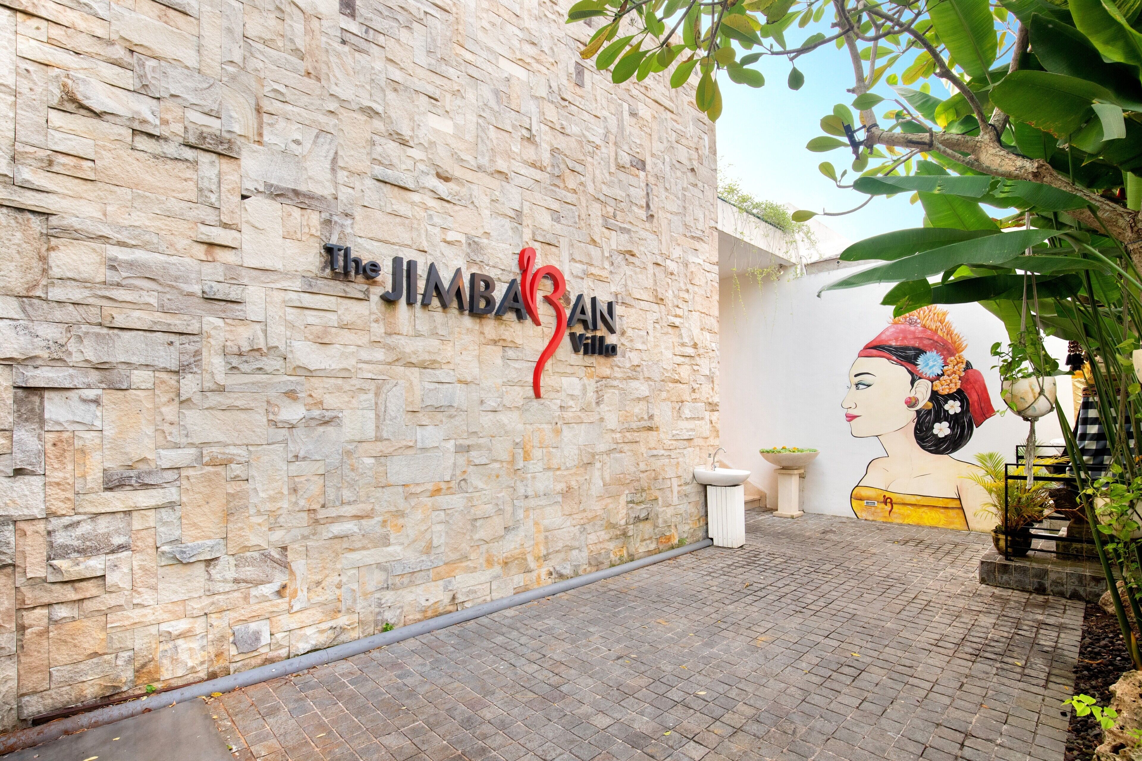 Un muro de piedra con un cartel que dice "The JIMBAAN Villa".