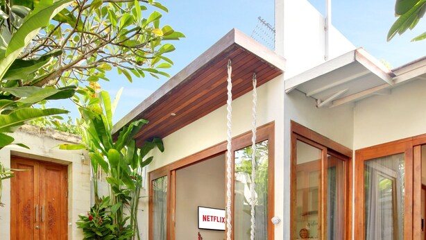 Una casa moderna con piscina, un comedor con mesa en forma de corazón y una zona de estar acogedora con sofá y cojines.