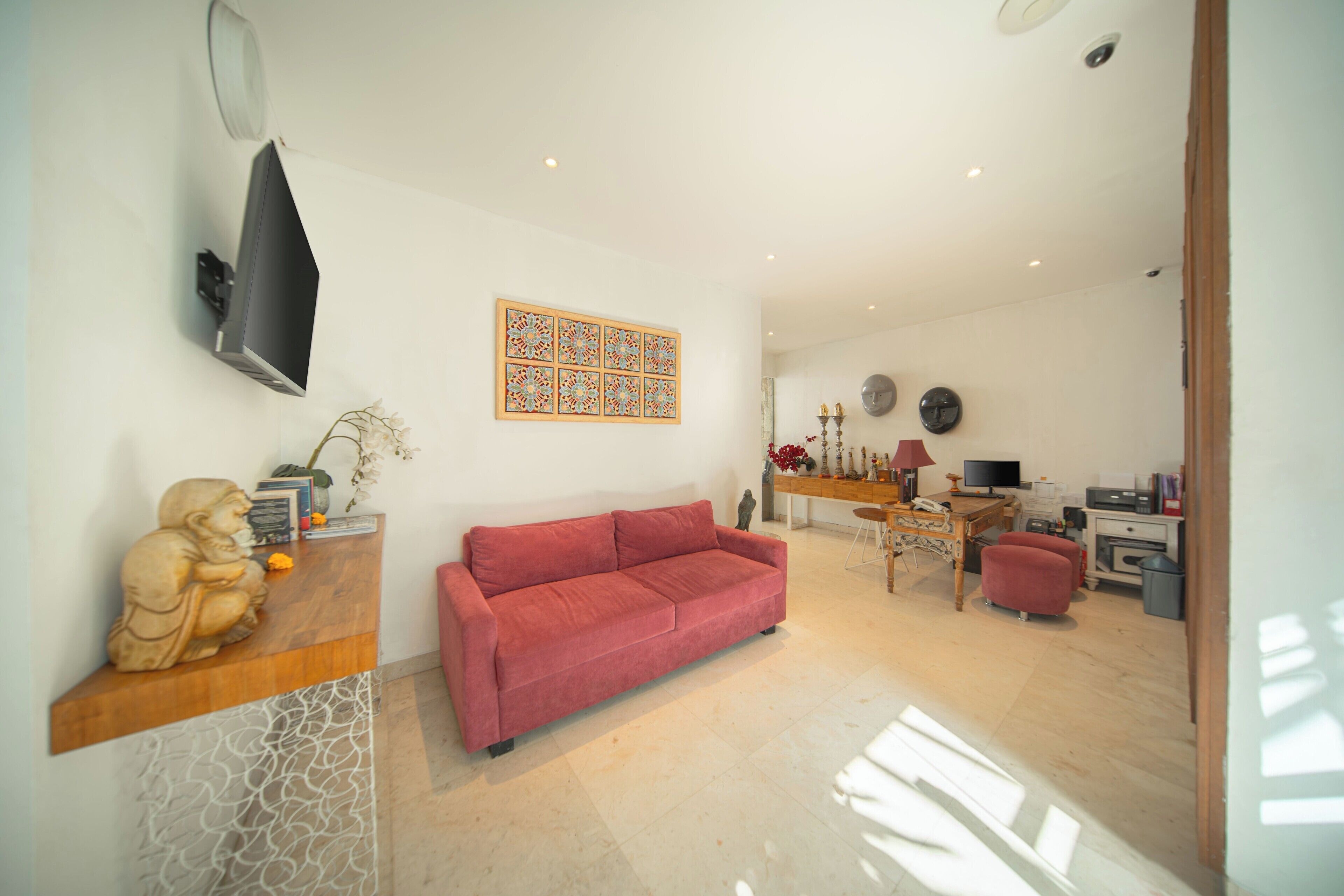 A modern living room with a red sofa, a wooden coffee table, and a TV mounted on the wall.