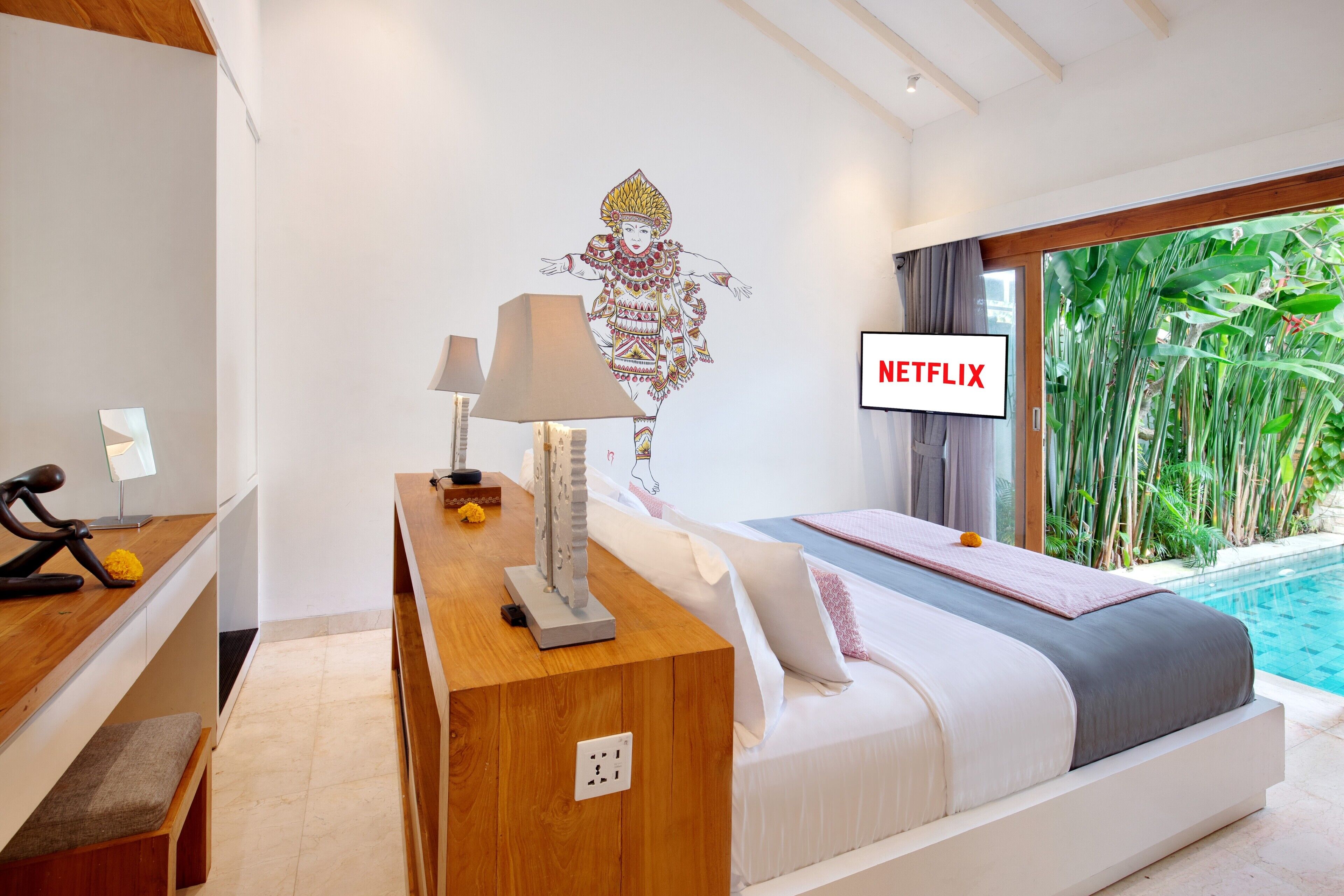 Une chambre d’hôtel moderne équipée d’un lit, d’une table de chevet, d’une lampe et d’un téléviseur fixé au mur qui affiche l’application « NETFLIX ».