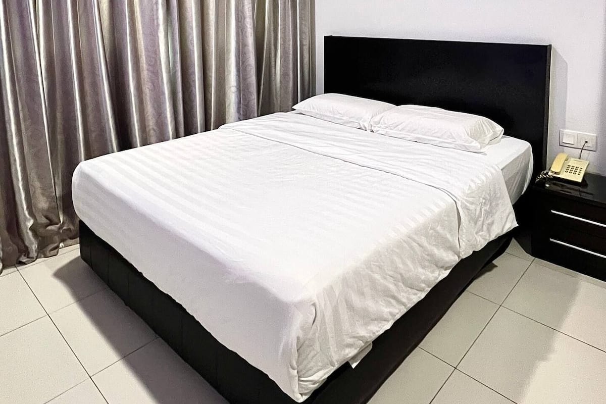 A neatly made bed with white linens in a hotel room.