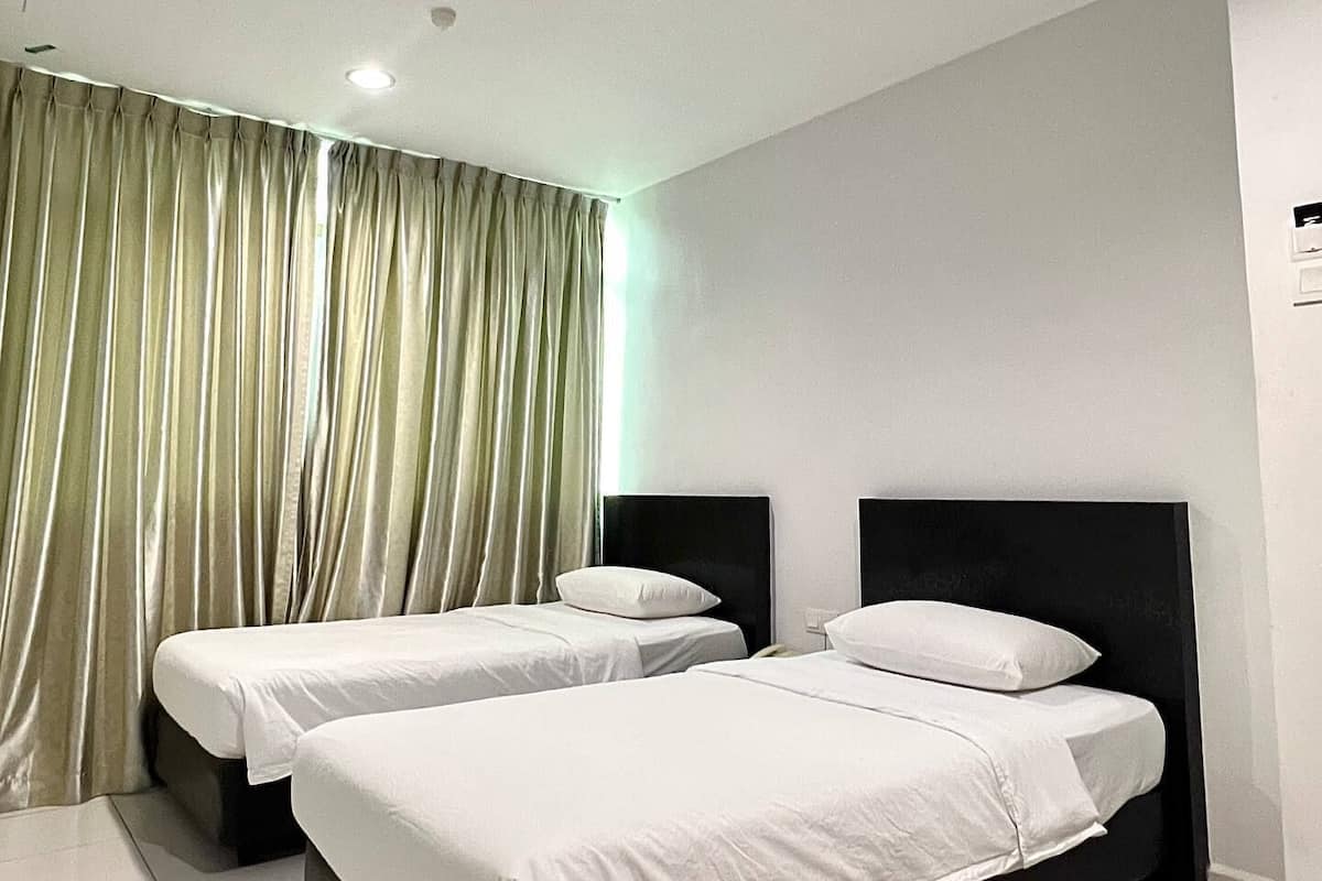 A hotel room with two beds, a large window with curtains, and a ceiling light.