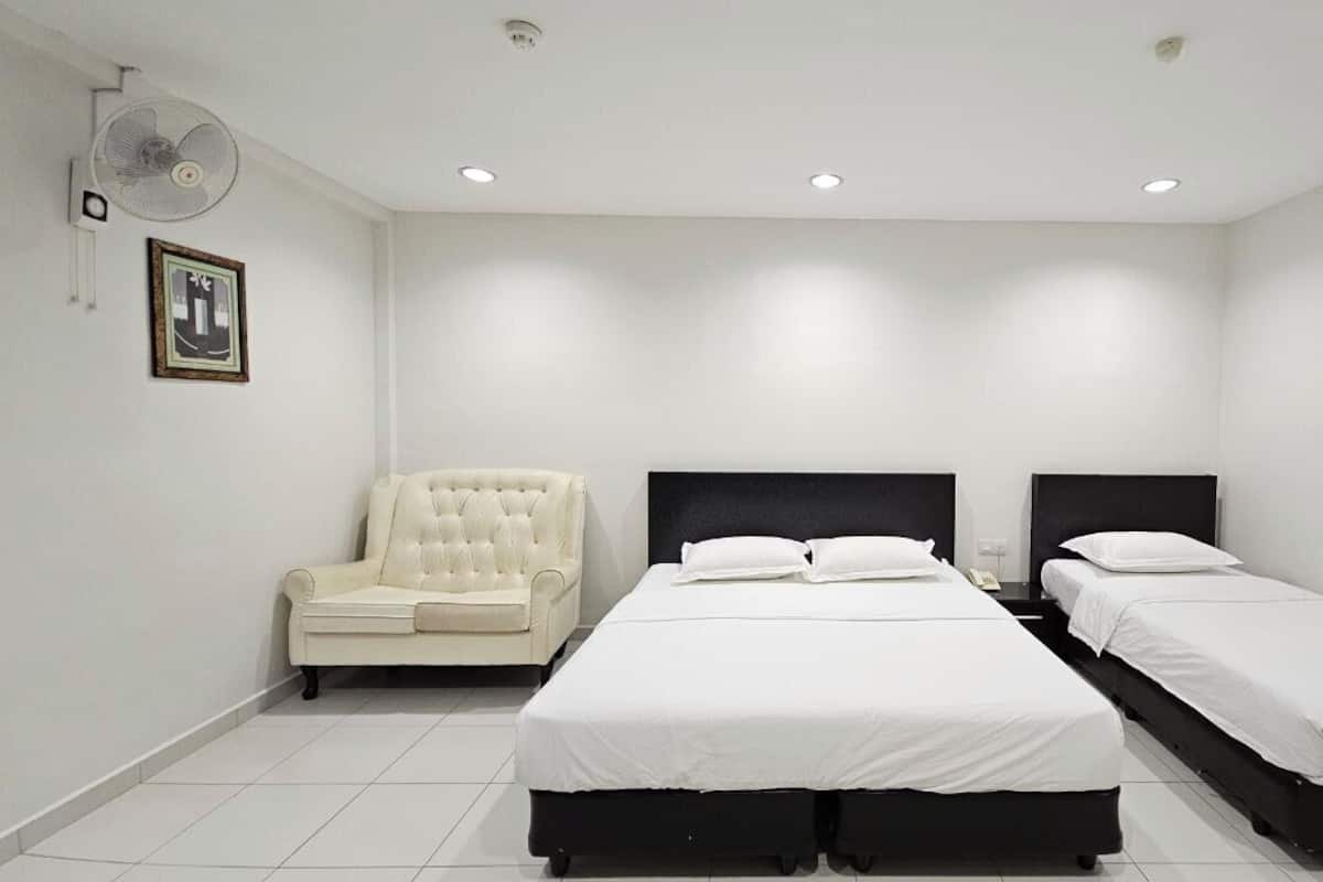 A bedroom with a large bed, a smaller bed, a chair, and a wall-mounted fan.