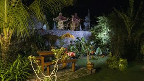 Un jardín con un banco, un árbol pequeño y una estructura decorativa.