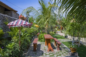 A garden with stone pathways, wooden benches, and a checkered umbrella.