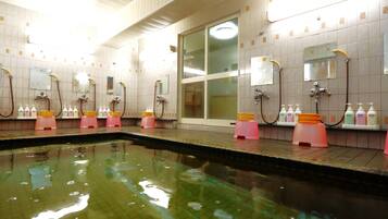 Baño público con varios lavamanos, espejos y una zona de piscina.