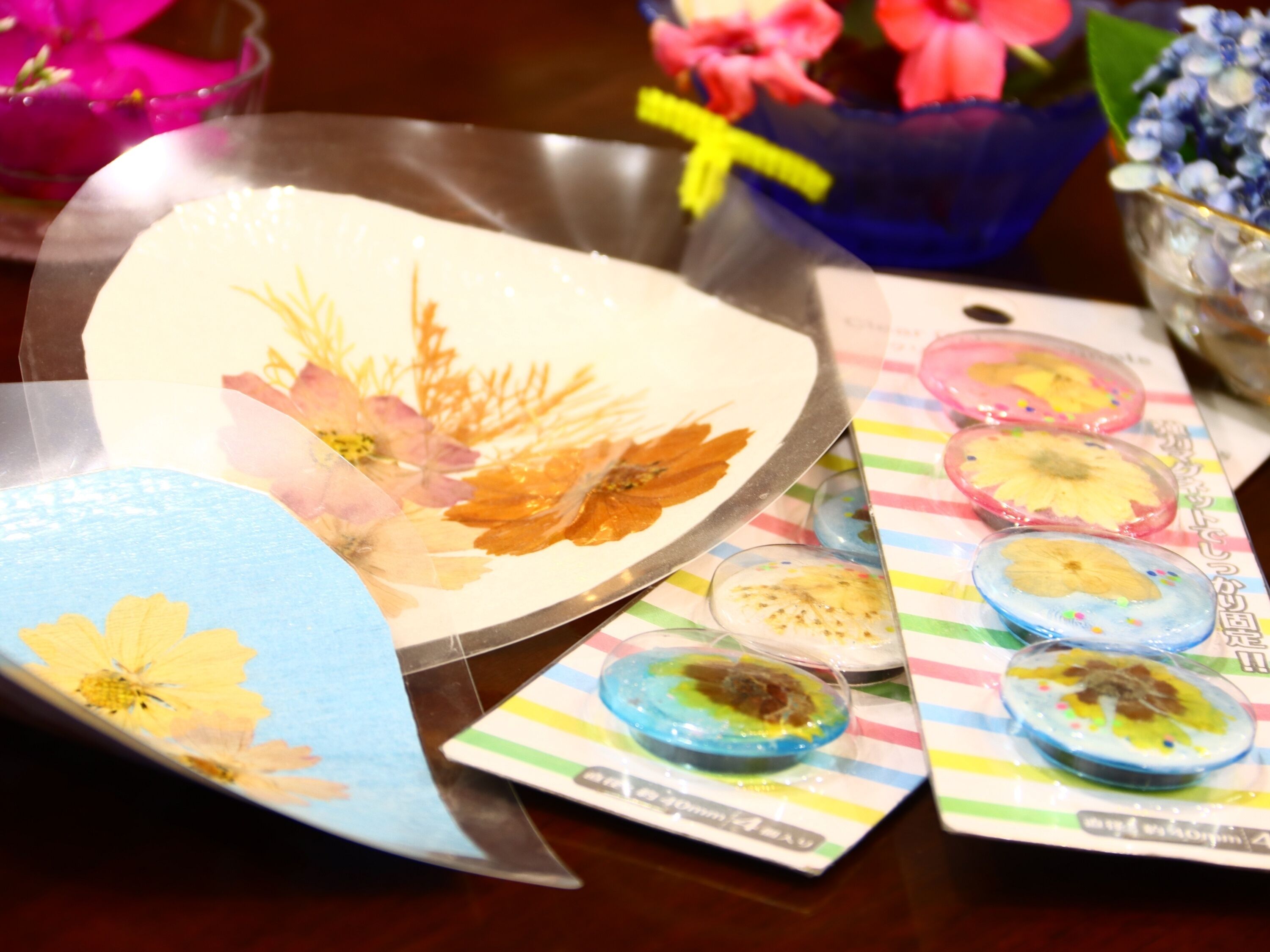 A table with a floral-patterned plate, a blue and yellow card, and several small round dishes with colorful toppings.