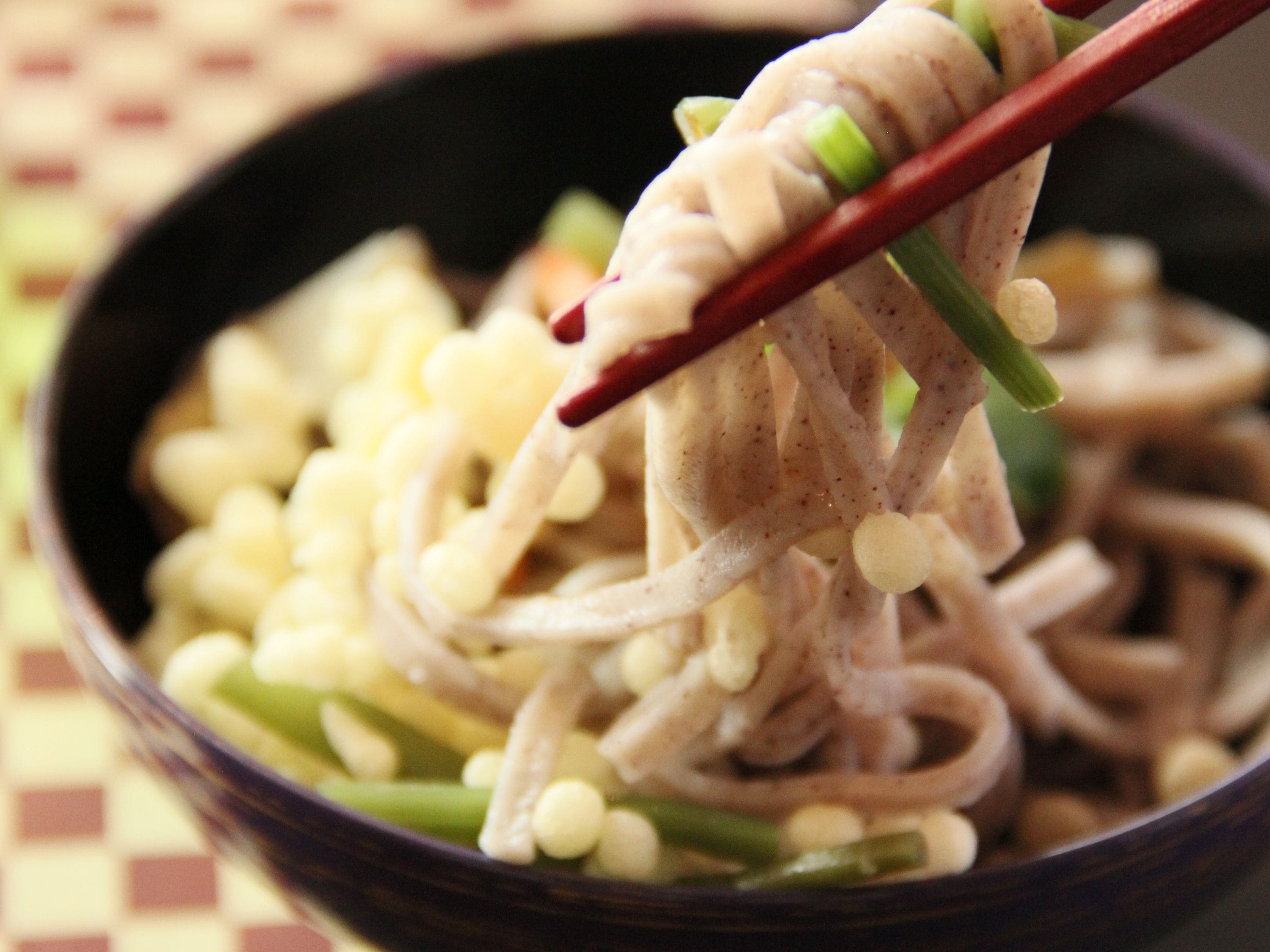 A bowl of noodles with chopsticks lifting a portion.