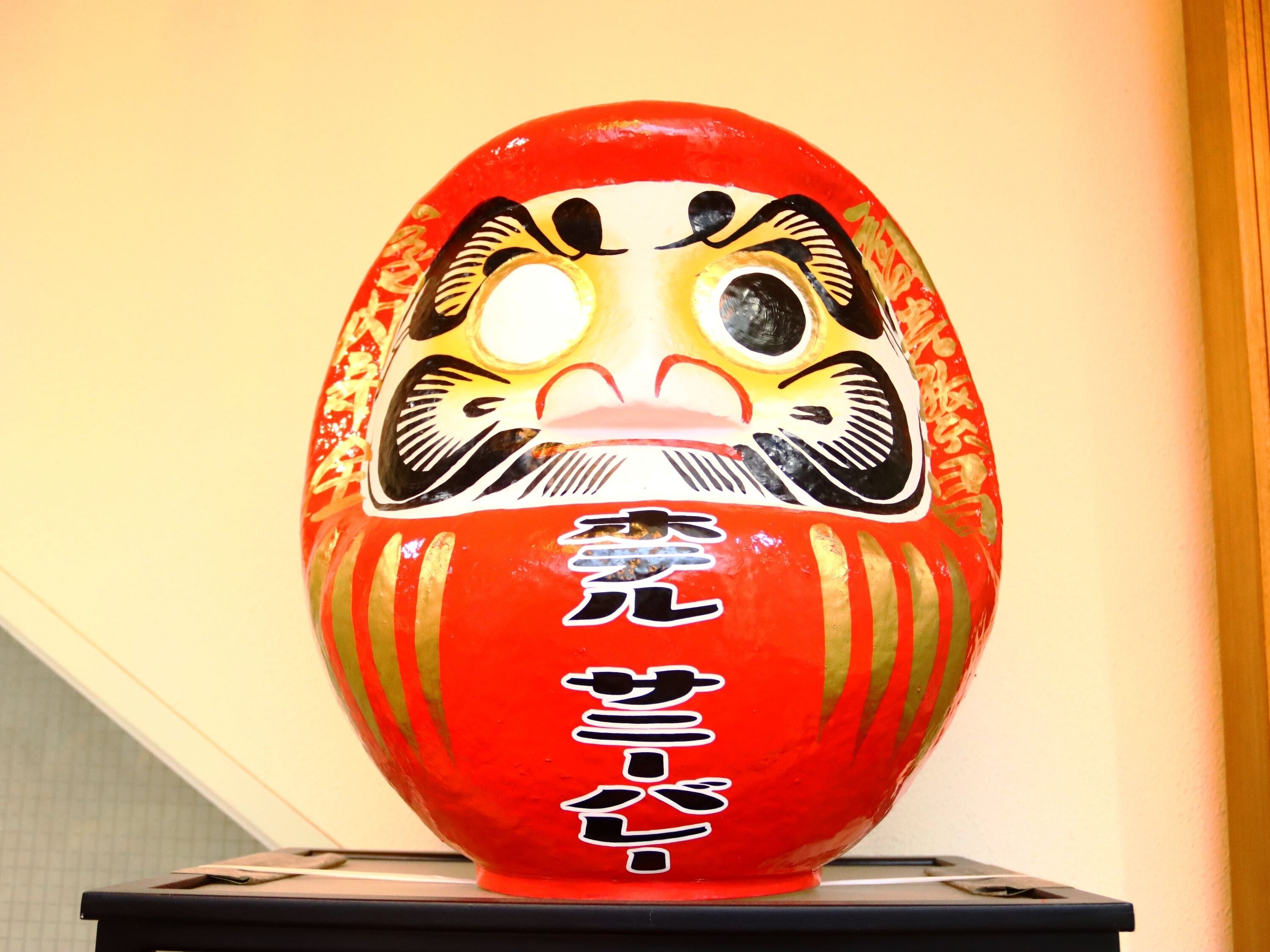 Un objeto decorativo rojo y dorado con caracteres japoneses.