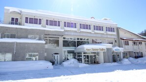 Ein Hotel mit Namensschild, überdachter Einfahrt und Schnee auf dem Boden.