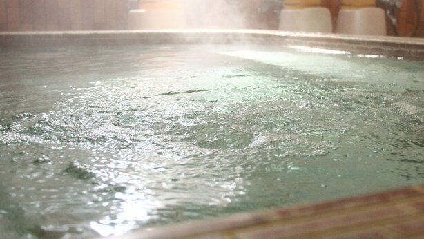 Ein Whirlpool mit gefliestem Beckenrand und einer Holzvertäfelung im Hintergrund.