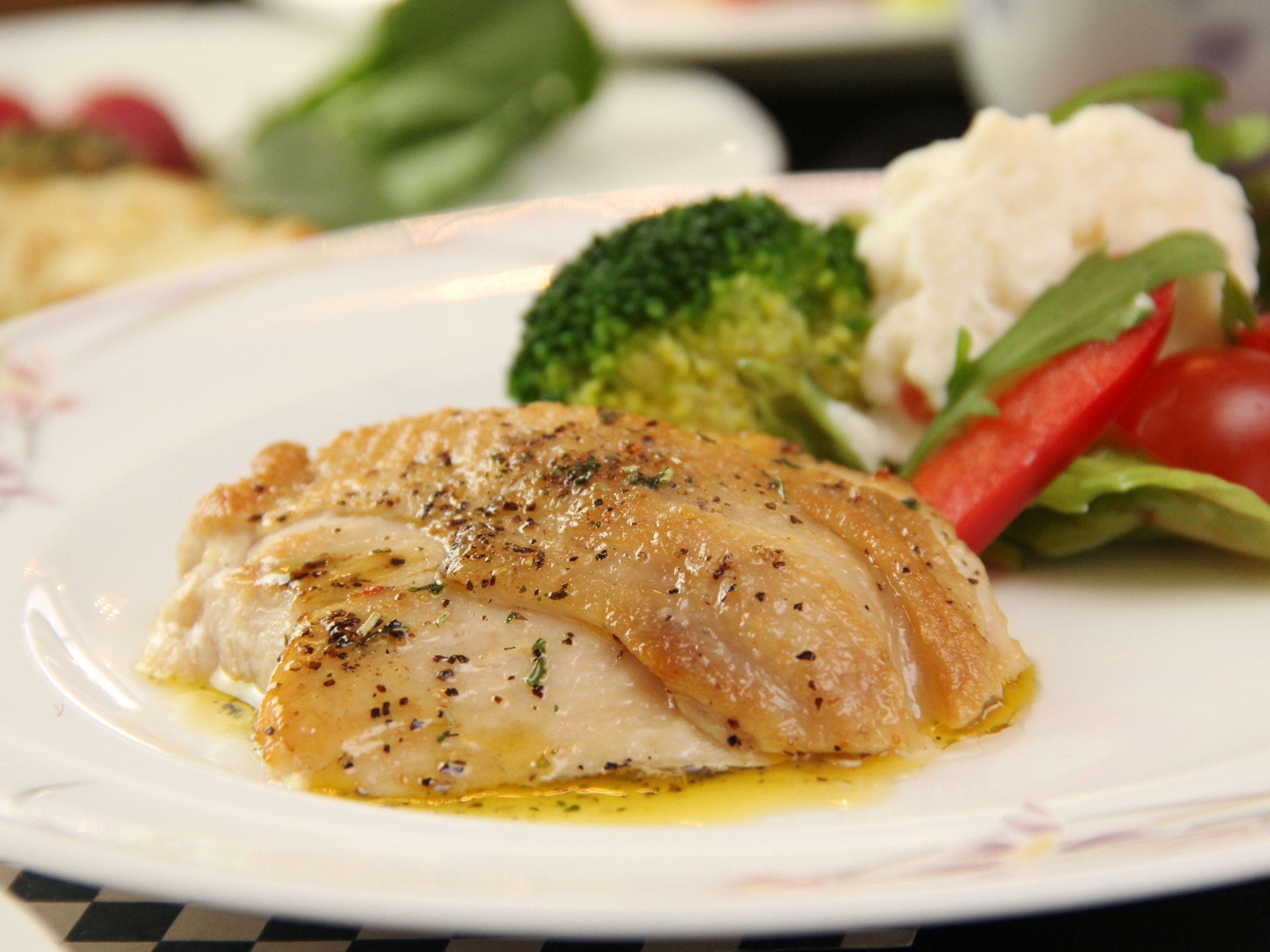 A plate with a piece of fish, broccoli, and a small salad.