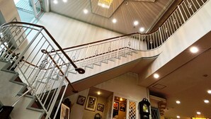 Ein mehrgeschossiges Interieur mit Treppe, einer Kandelaber und einer Uhr.