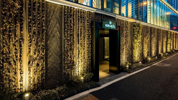 Fachada moderna de hotel con jardines verticales y una entrada destacada.