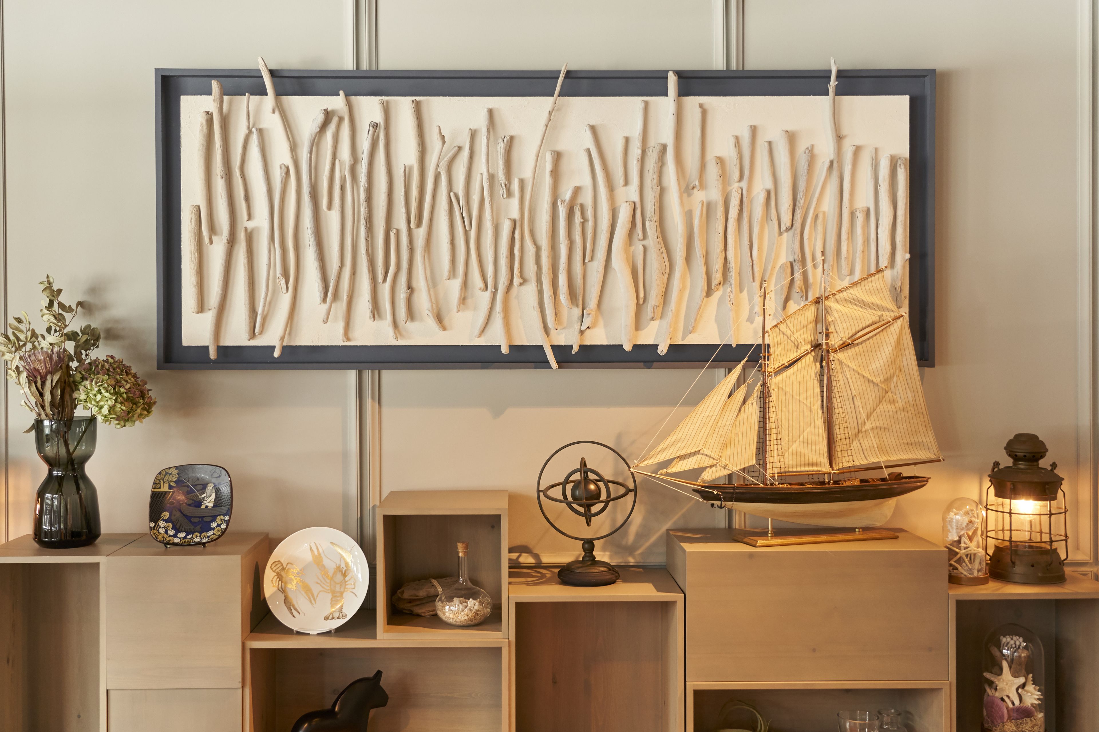 Une pièce dans laquelle on trouve une grande œuvre d’art abstrait accrochée au mur, un modèle de voilier et divers objets décoratifs disposés sur des étagères.