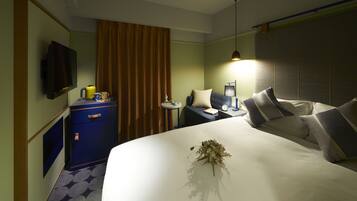 A hotel room with a bed, a desk, a chair, a television, and a nightstand.