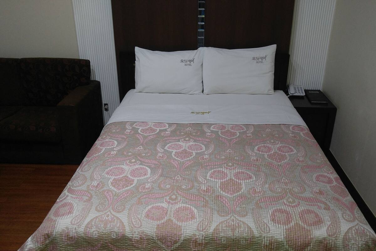 Een hotelkamer met een bed, nachtkastje, telefoon en een bank.