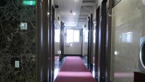 A hallway with a red carpet, marble walls, and a ceiling with recessed lighting. - Odyssey  Hotel (Chungju)