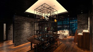 A modern interior with a wooden dining table, a black metal shelving unit, and a white sofa. - Hotel Resol Akihabara (Tokyo)