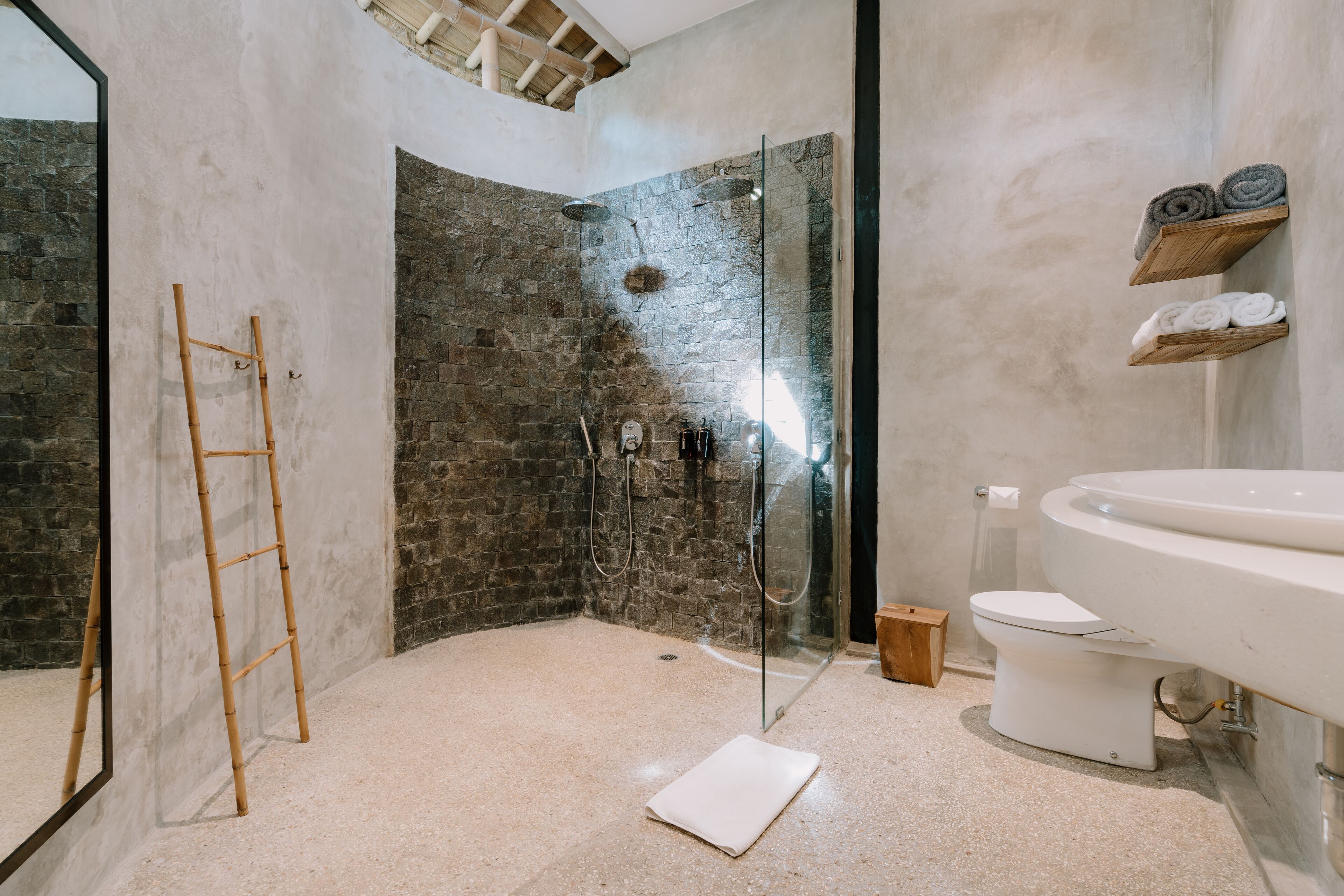 Un baño moderno con ducha de vidrio, inodoro blanco y un espejo grande.