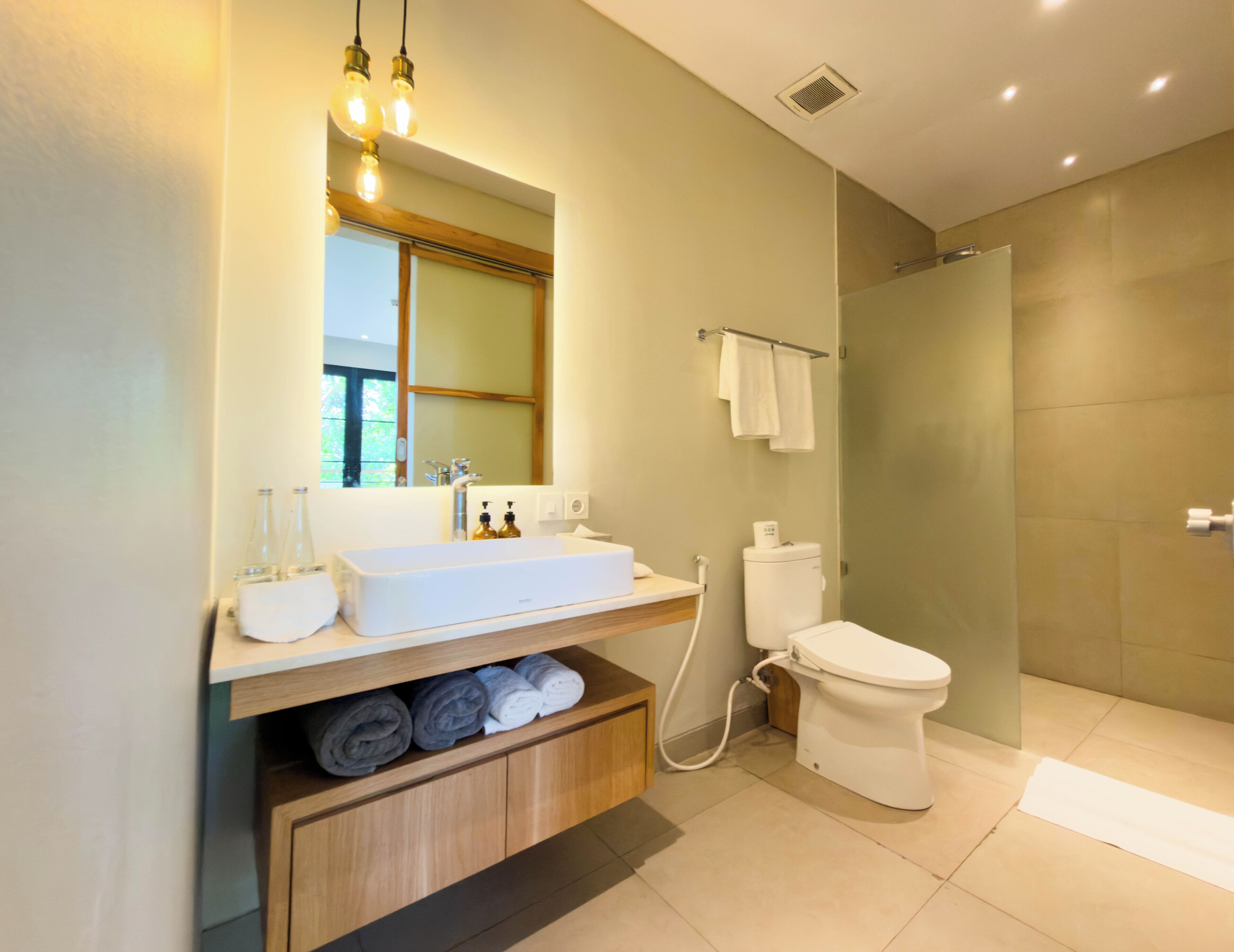 A modern bathroom with a large sink, toilet, and shower area.