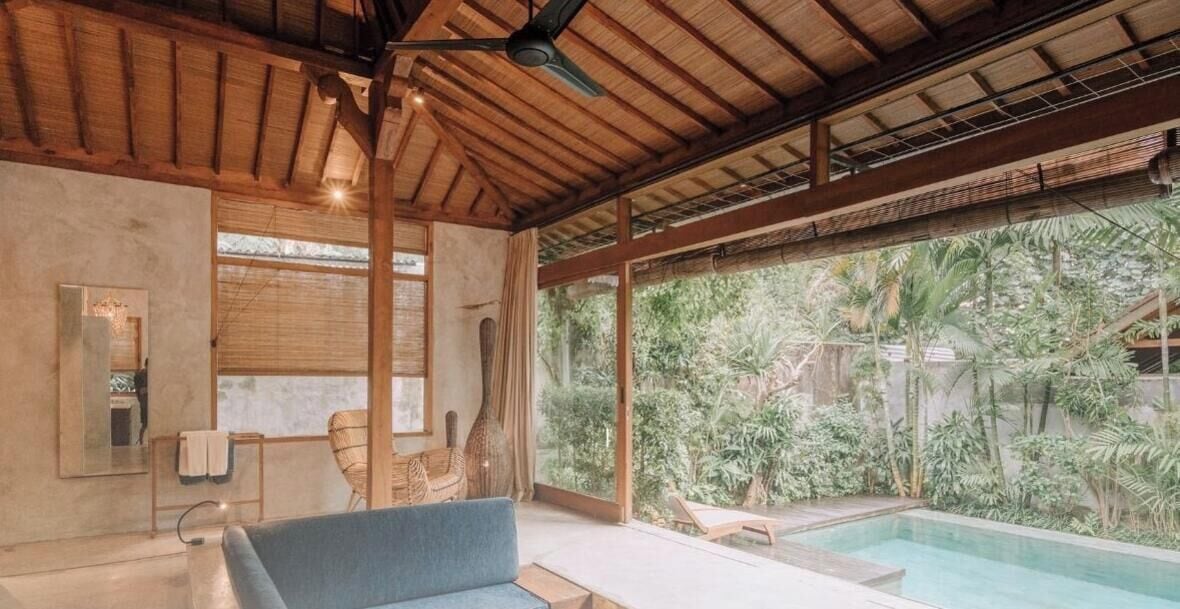 Una habitación con un ventanal grande, ventilador de techo, sofá y piscina.