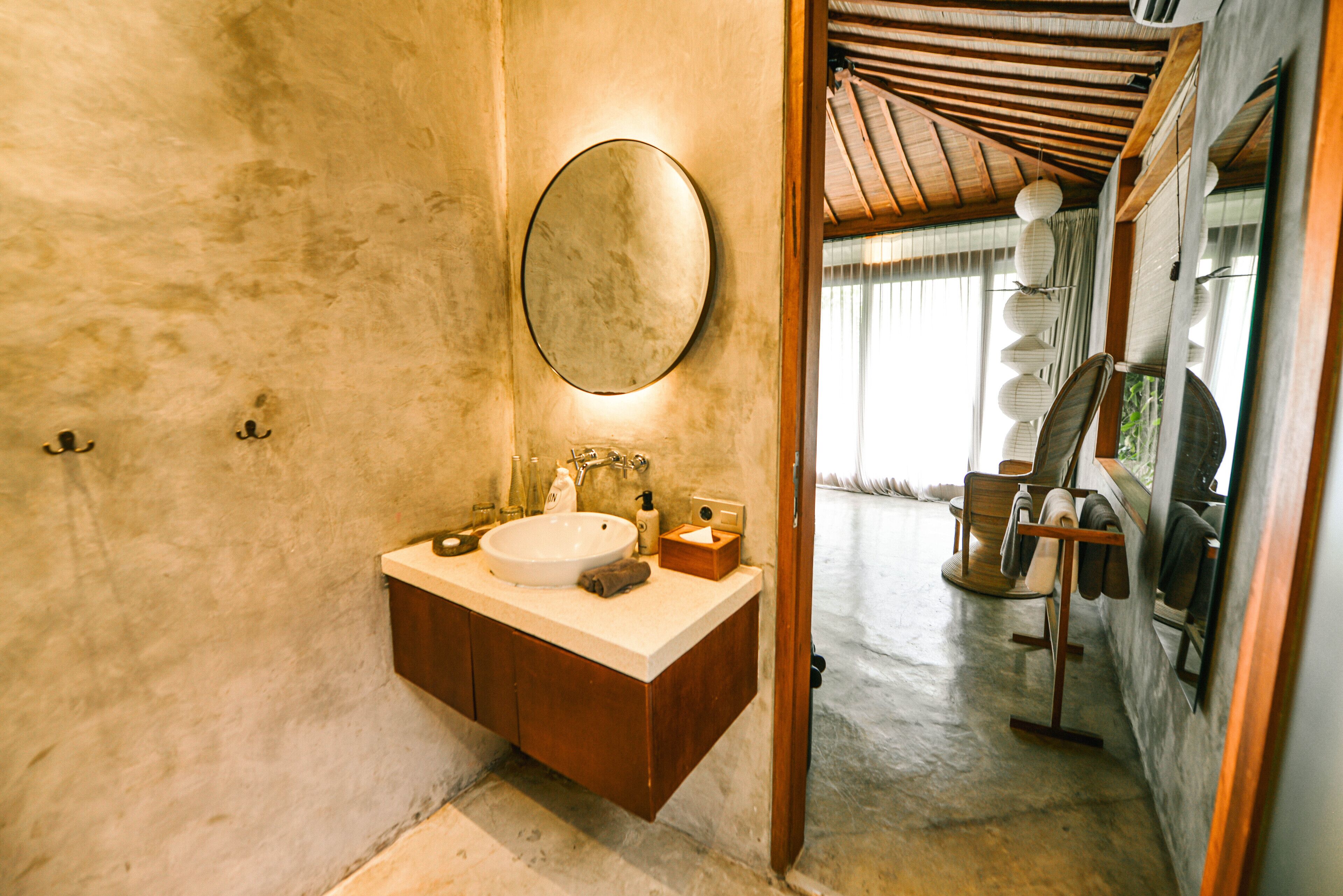 A bathroom with a wooden vanity, a round mirror, and a sink.