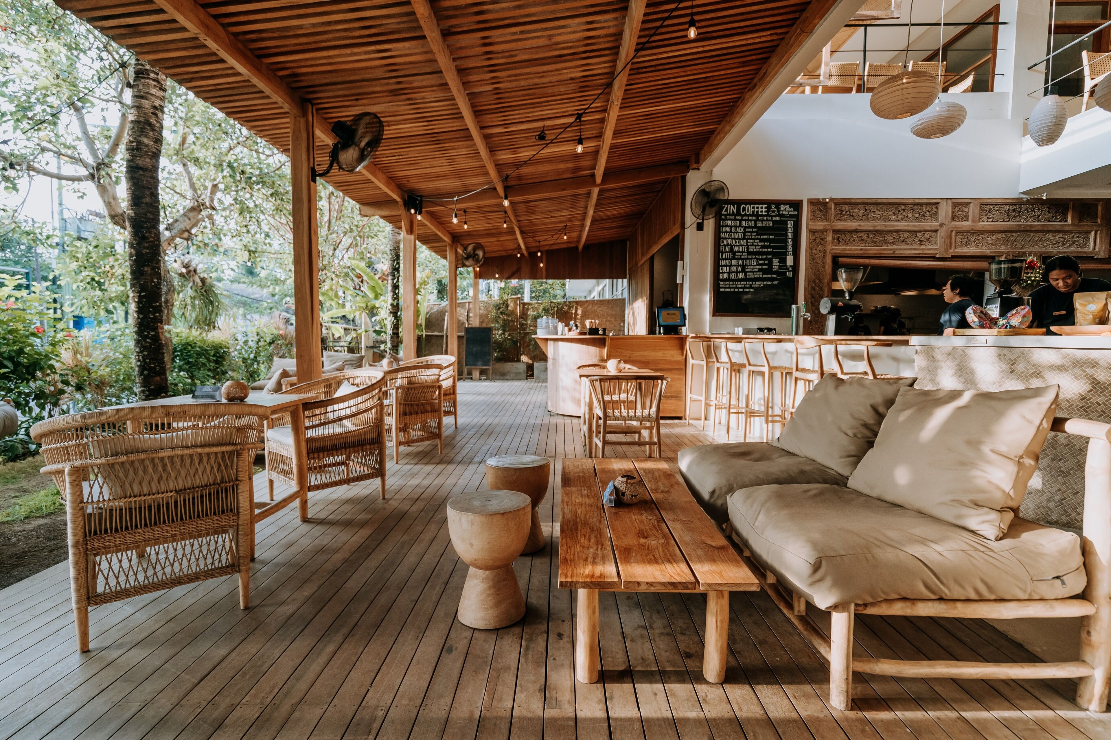 An outdoor seating area with wicker furniture, a wooden table, and a cushioned bench.