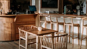Un café chaleureux, avec un décor intérieur accueillant, des meubles en bois, un tableau noir servant de menu et un ventilateur.