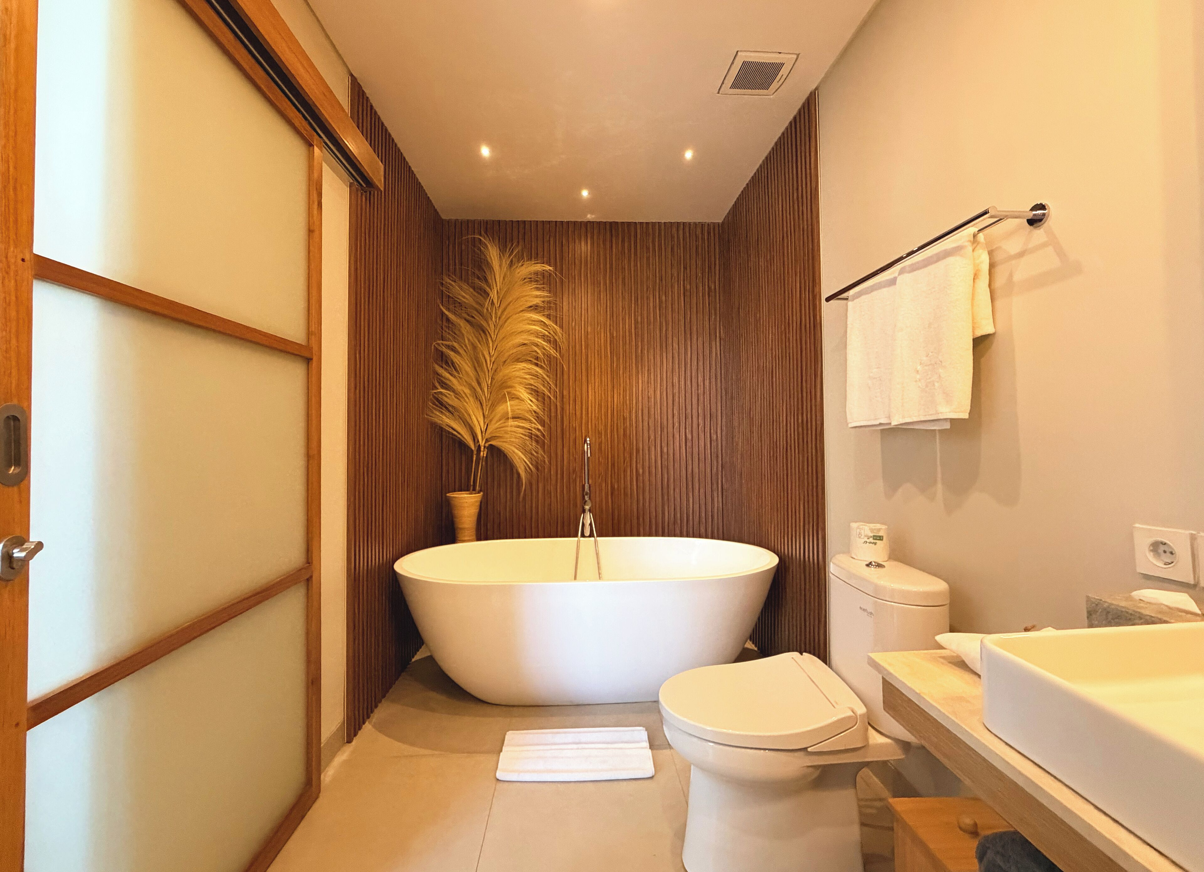 A modern bathroom with a freestanding bathtub, a toilet, and a sink.