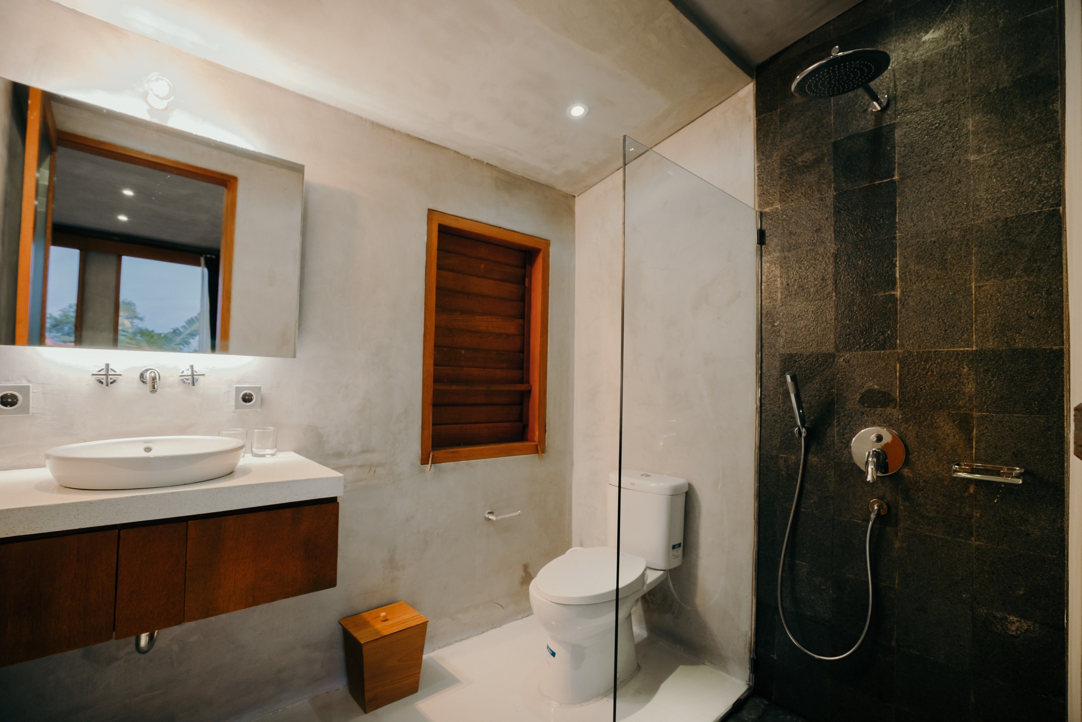 A modern bathroom with a large mirror, a sink, a toilet, and a shower area.