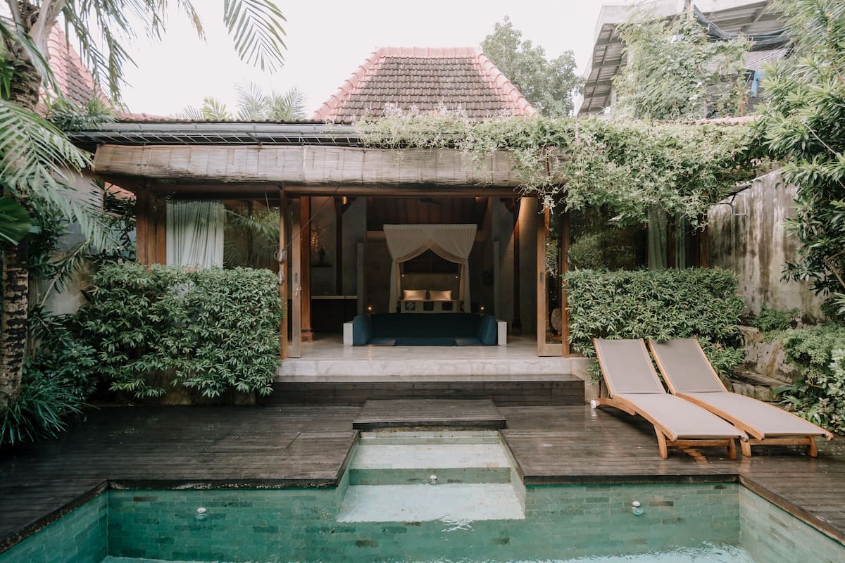 Un espace aménagé au bord de la piscine, avec une terrasse en bois, deux chaises longues et une petite piscine.