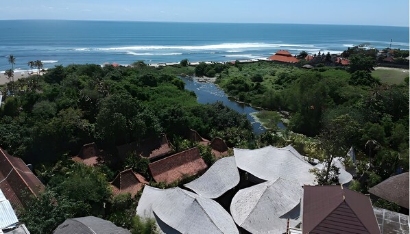 A coastal village with traditional houses, a river, and the ocean in the background.