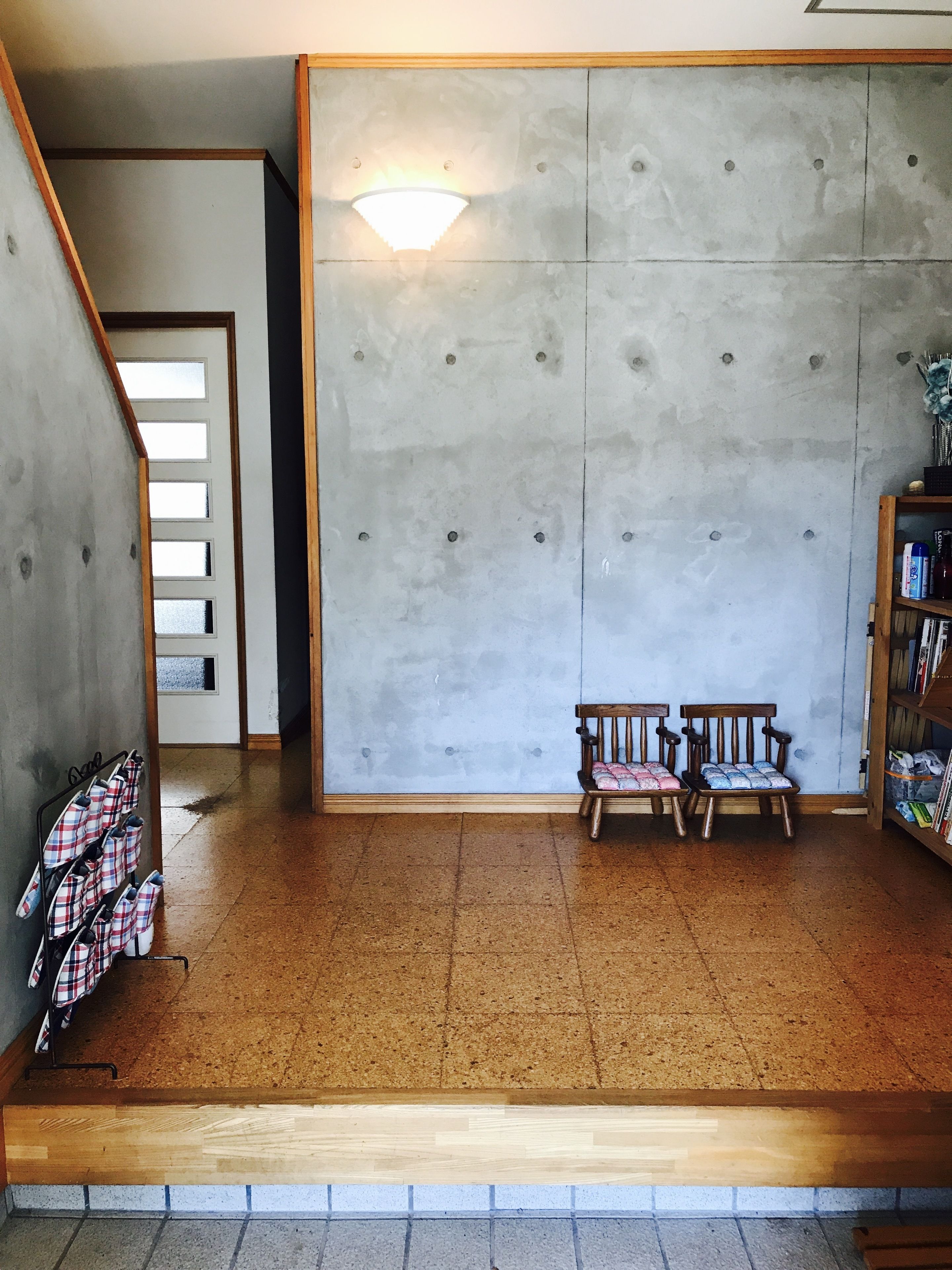 Una habitación con pared de concreto, un banco de madera, un perchero de metal y una estantería.