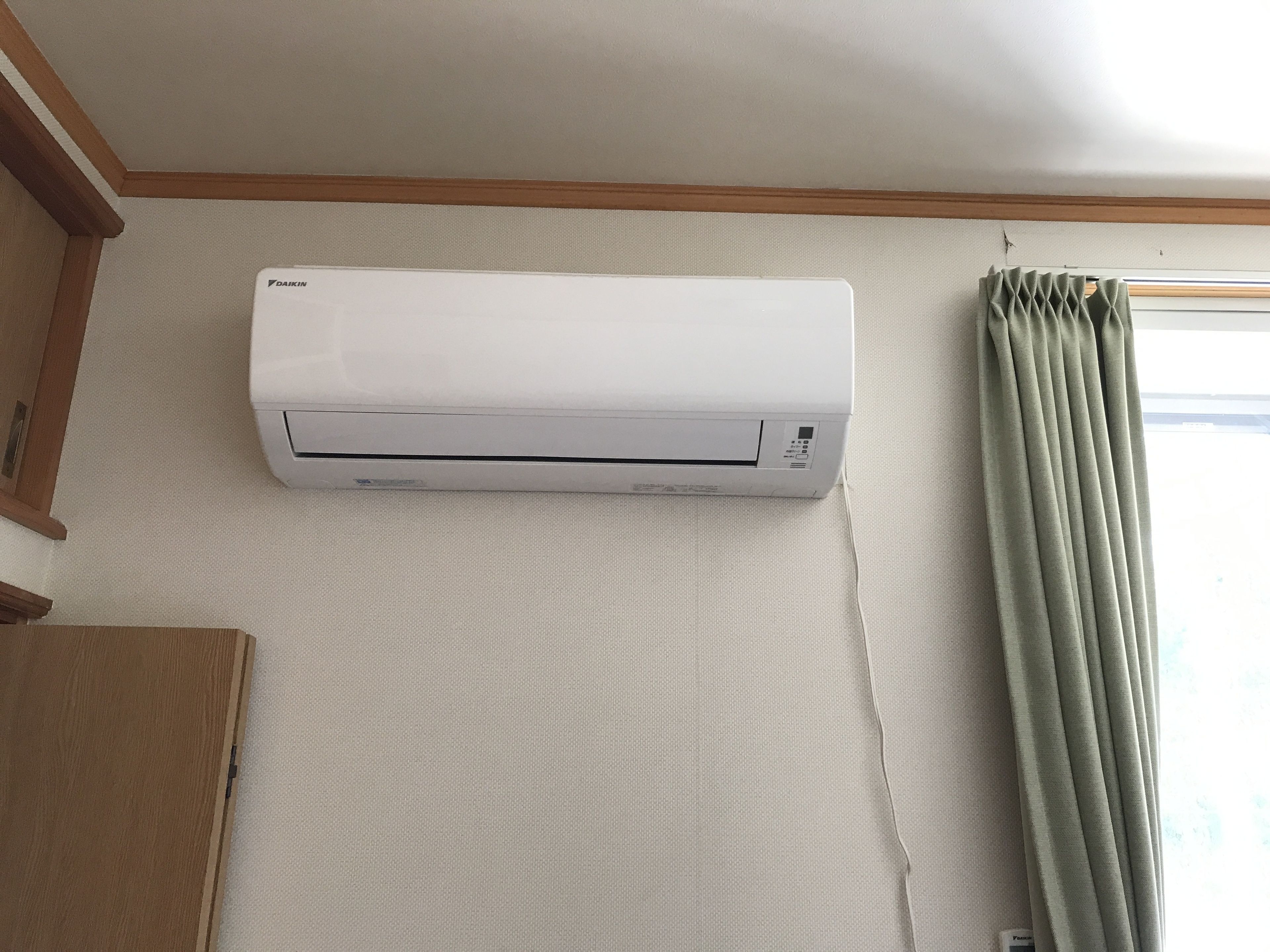 A white Daikin air conditioner mounted on a wall with a wooden trim ceiling.