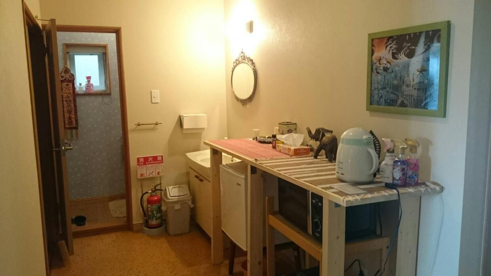 Une petite salle de bain comprenant des toilettes, un lavabo et une petite fenêtre. On y trouve également un extincteur et un miroir accroché au mur.