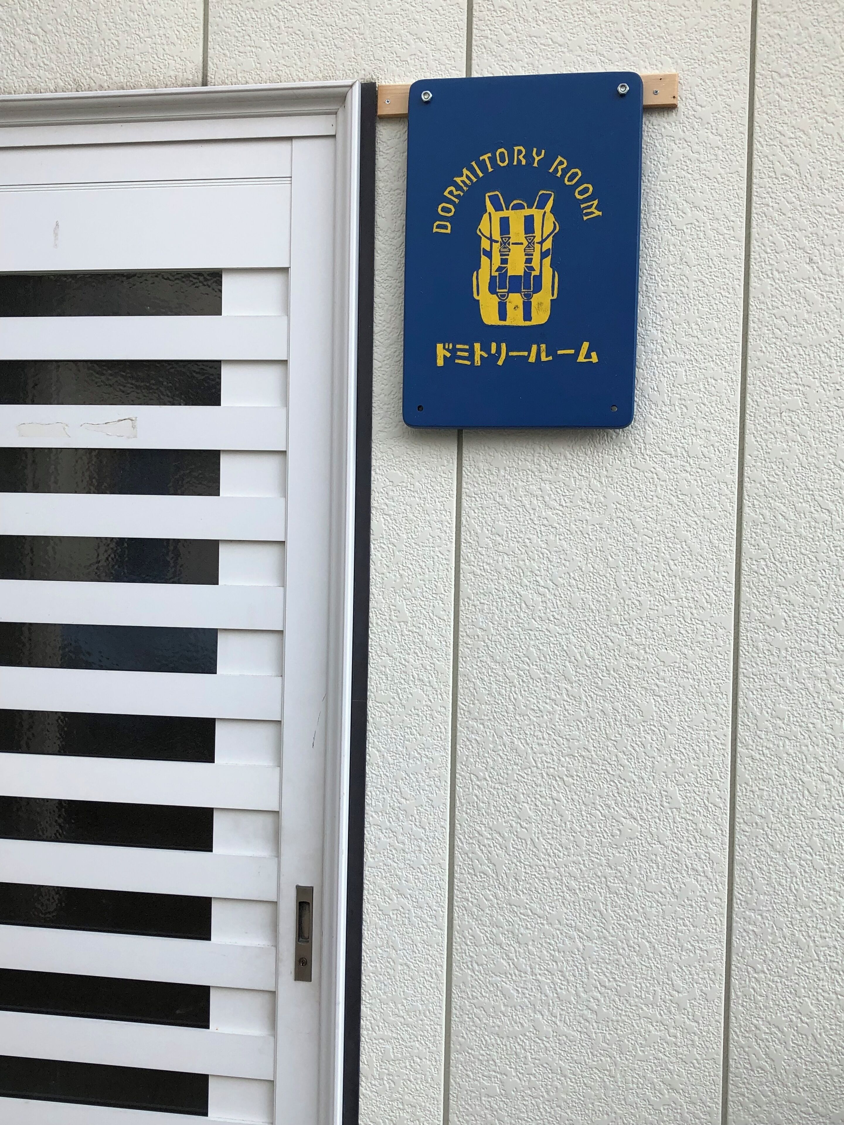 A dormitory room sign with a bed and a window.
